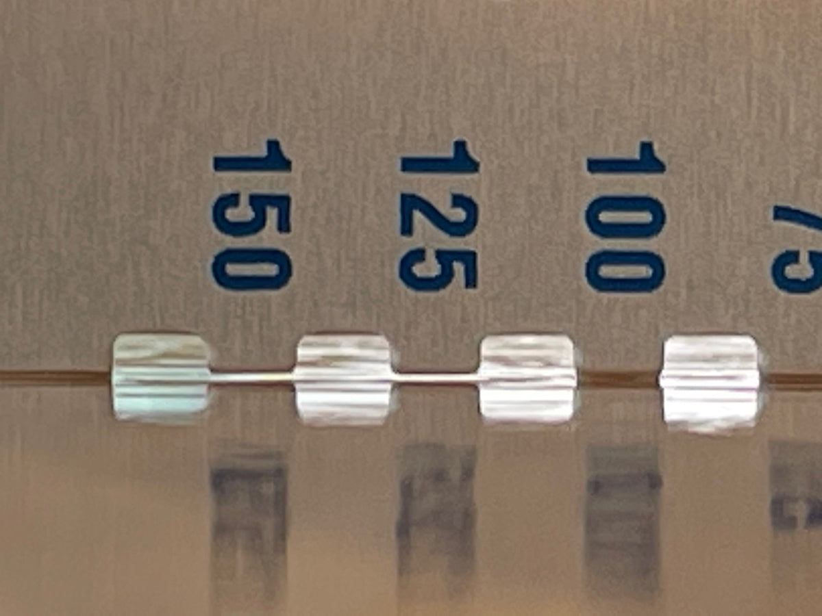 Nahaufnahme einer transparenten Flüssigkeit in einem Behälter mit blauen Messmarkierungen, die die Volumen 75, 100, 125 und 150 Einheiten anzeigen. Der Flüssigkeitsstand liegt leicht über der Marke 125.